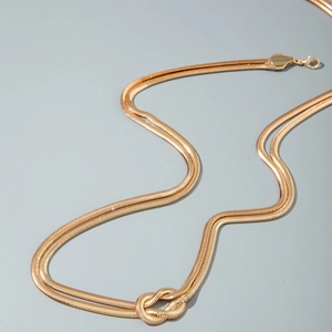 Dettaglio della catena a serpente dorata con nodo decorativo e chiusura a moschettone