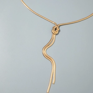 Dettaglio catena corpo dorata con nodo decorativo e nappine pendenti eleganti