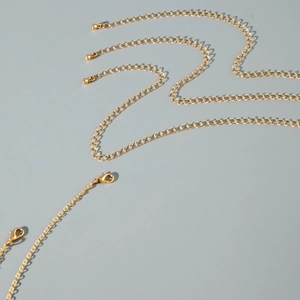 Close-up of golden multi-layered waist chain with lobster clasp and beaded extender chain