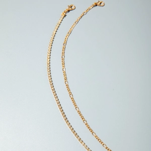 Detailed macro view of gold-tone tennis chain and Figaro chain with lobster clasp