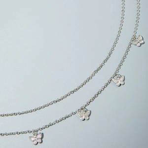 Close-up of double-layer silver chain body link with intricate butterfly pendants