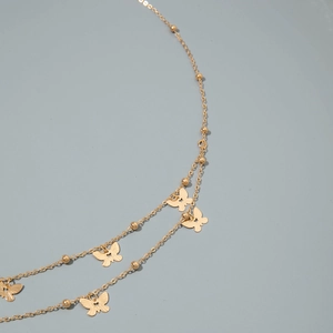 Macro shot of double-layer gold butterfly pendants and beads on a sleek metal body chain