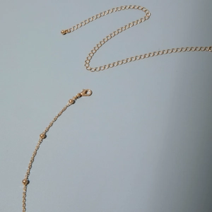 Detail of gold metal body chain featuring lobster clasp and adjustable link extender