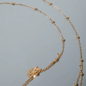 Detail of layered gold butterfly waist chain with polished beads and metallic finish