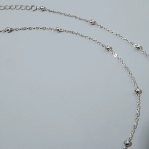 Macro detail of silver body chain with polished metal beads and lobster clasp closure