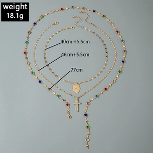 Detailed view of triple-layered gold cross necklace set with gemstone and size markings