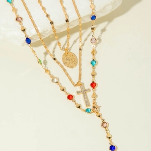 Layered gold necklace featuring a sparkling cross pendant and multicolor gemstones sets