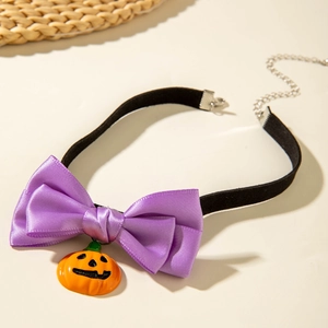 Close-up of Halloween choker with purple bow and orange pumpkin charm on black band