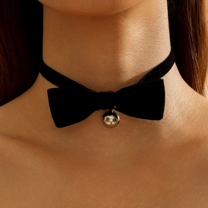Macro view of black velvet bow choker necklace with a polished silver bell pendant detail