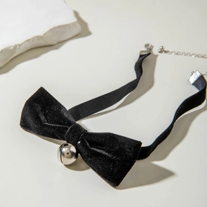 Close-up of black bow choker with silver bell and adjustable metal chain detail