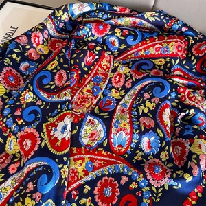 Detailed macro view of the luxurious paisley print silk scarf in navy and red shades