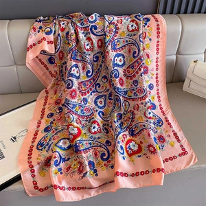 Detail of peach paisley silk scarf with floral patterns on a luxury leather couch