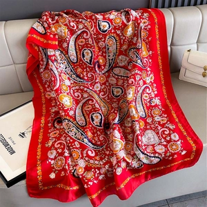 Detail of red paisley silk scarf with floral patterns on a leather bench