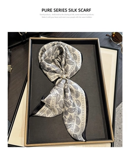 Detail of silk scarf with paisley pattern and pearl metal ring buckle in gift box