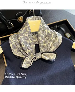 Detailed view of paisley silk scarf styled with luxury bag and watch on wood background