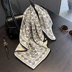 Vintage paisley silk scarf in beige and black draped on a luxury leather handbag