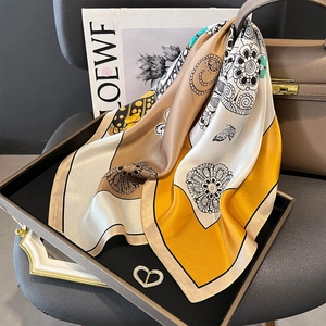 Carré de soie vintage à motif floral jaune moutarde et marron sur un plateau en cuir