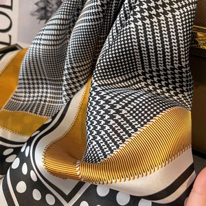 Detailed view of silk scarf featuring houndstooth pattern and yellow borders