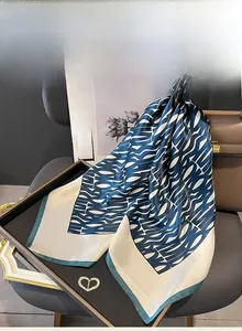 Detail view of luxurious mulberry silk scarf with blue wave patterns on a black tray