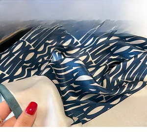 Macro detail showing fine hand-rolled green edges on silk scarf with lettered print