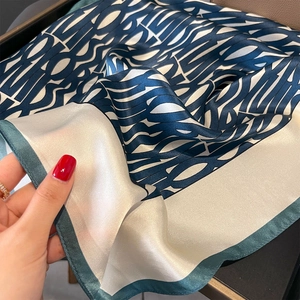 Luxurious navy and beige silk scarf featuring abstract geometric letters and green edges