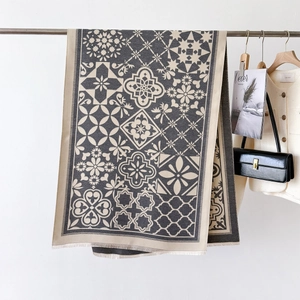 Gros plan d'une écharpe épaisse à motif géométrique beige et gris avec bords frangés