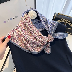 Sciarpa in seta a fiori rosa e blu legata elegantemente su un top blu navy scuro