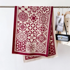 Détail d'une écharpe bohème rouge et crème avec motifs floraux complexes et finitions franges