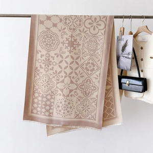 Détail d'un châle à imprimé floral géométrique avec pompons suspendu à un cintre en métal