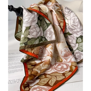 Elegant silk scarf with vintage rose print and orange border shown in styled display