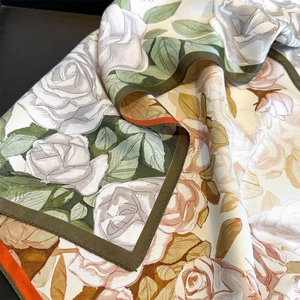 Macro view of realistic rose print and hand-rolled edges on a silk twill scarf