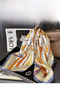 Detail of silk twill square scarf with retro chain print draped on a leather handbag