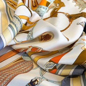 Macro detail of silk scarf showing equestrian horse bit pattern and twill texture