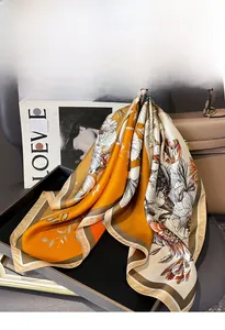 Detail of silk twill square scarf with floral print draped over a leather handbag