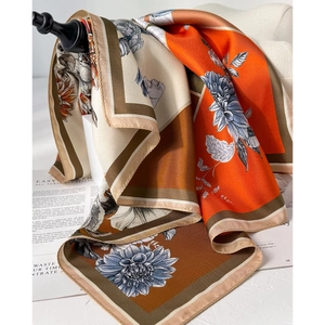 Detail of silk scarf with floral print and satin texture in orange and brown tones
