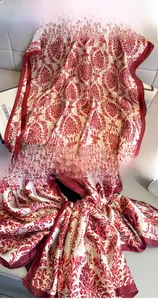 Détail d'un foulard en soie damassé rouge et blanc montrant la texture brillante