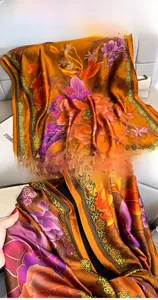Detail view of floral silk scarf showing premium orange fabric and lockstitch edge finish