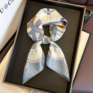 Silk twilly scarf with horse harness print tied in a bow on a luxury display tray