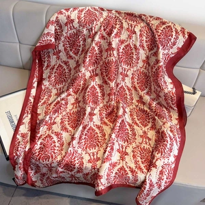Élégante écharpe en satin de soie damassé rouge et blanc sur un canapé en cuir gris