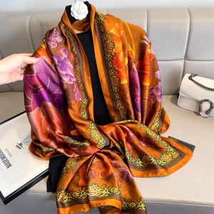 Floral orange silk scarf draped as a sun protection shawl with elegant vintage borders