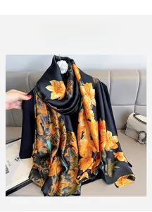 Close-up of printed silk scarf with orange floral pattern and camellia brooch accent