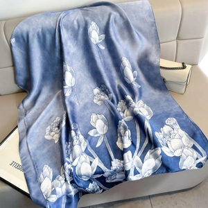 Elegante blauwe zijden sjaal met wit lotuspatroon op een lederen bankstel
