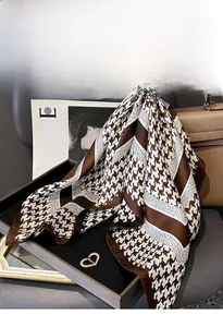 Detail of silk twill square scarf with brown houndstooth pattern draped over a leather bag