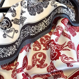 Macro detail of high-quality silk scarf with baroque scroll and red heart patterns