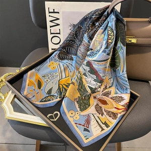 Blue and yellow botanical print mulberry silk square scarf elegantly draped over a tray