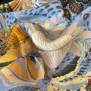 Blue silk scarf with yellow feather print showing premium satin texture and draping