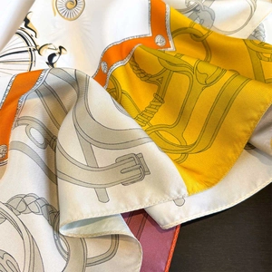 Detail of silk scarf with equestrian prints and hand-rolled edges in luxury orange tones