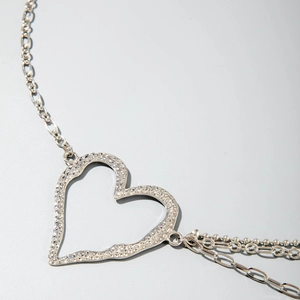 Dettaglio macro del ciondolo a cuore in argento con trama martellata e catene a strati multipli