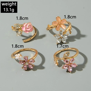 Detalle del set de cuatro anillos florales con rosa rosa, cristales y perlas en tono oro