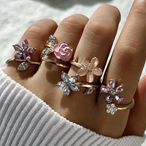 Detalle del juego de anillos de flores doradas con pétalos de esmalte y perlas